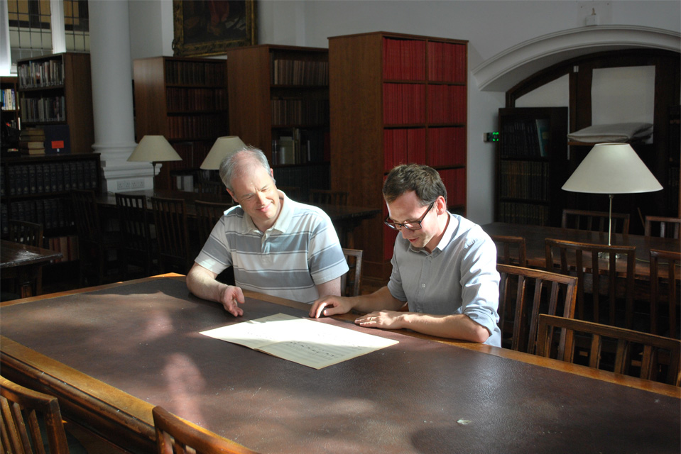 Two men studying a score in the H漫画 Library